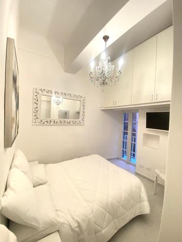una camera bianca con un letto bianco e un lampadario a braccio di Ilia a Lerici