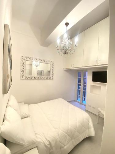 a white bedroom with a white bed and a chandelier at Ilia in Lerici
