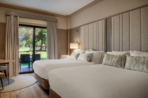 a hotel room with two beds and a large window at Hacienda Son Antem Golf Resort, Autograph Collection in Llucmajor