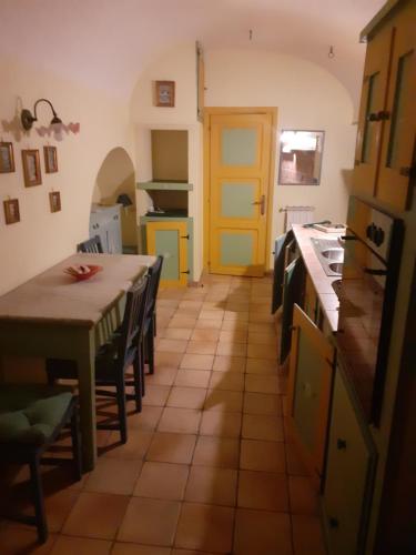 チェラーノにあるCasa nel vicolettoのキッチン(テーブル、椅子付)、黄色のドア