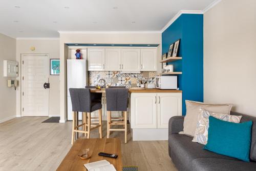 uma cozinha e sala de estar com um sofá e uma mesa em Stylish flat with balcony overlooking the sea em Costa da Caparica