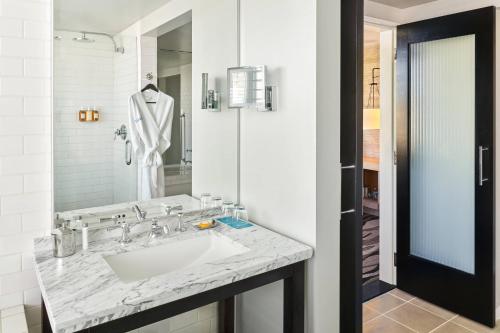 ein weißes Badezimmer mit einem Waschbecken und einem Spiegel in der Unterkunft Hotel Republic San Diego, Autograph Collection in San Diego