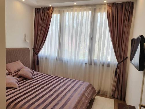 a bedroom with a bed and a window with curtains at Vila Kuća mira in Konjic
