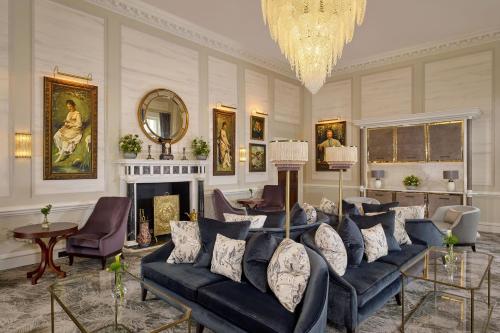 a living room with a blue couch and a chandelier at The Langley, a Luxury Collection Hotel, Buckinghamshire in Iver