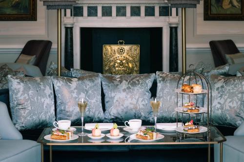a table with plates of food on a couch at The Langley, a Luxury Collection Hotel, Buckinghamshire in Iver