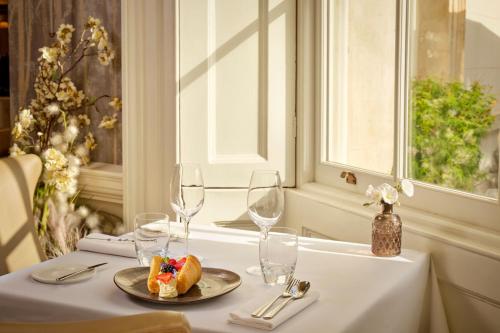 a table with a plate of food and wine glasses at The Langley, a Luxury Collection Hotel, Buckinghamshire in Iver