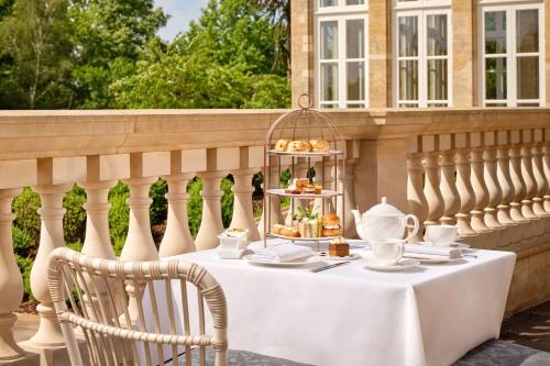 a white table with a tea set on a fence at The Langley, a Luxury Collection Hotel, Buckinghamshire in Iver