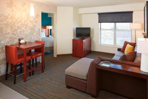 a hotel room with a couch and a table and a television at Residence Inn Minneapolis St. Paul/Roseville in Roseville