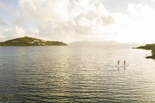 two people are standing on a paddle board in the water at The Ritz-Carlton St. Thomas in Benner