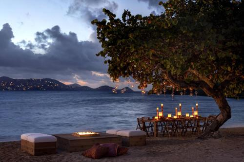 a table with candles and chairs on the beach at The Ritz-Carlton St. Thomas in Benner