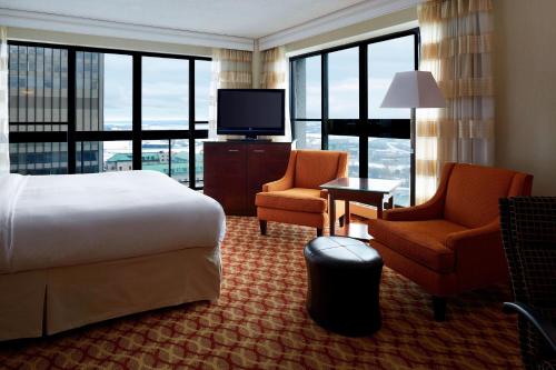 a hotel room with a bed and two chairs and a television at Ottawa Marriott Hotel in Ottawa