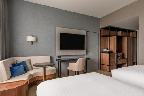 a hotel room with a bed and a couch and a tv at Geneva Marriott Hotel in Geneva