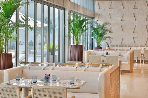 ein Restaurant mit Tischen und Stühlen und großen Fenstern in der Unterkunft The St. Regis Dubai, The Palm in Dubai