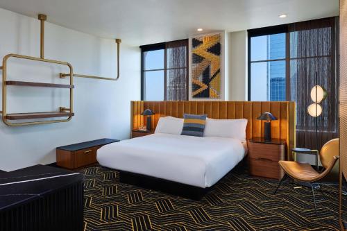 um quarto com uma cama, uma cadeira e janelas em W Minneapolis - The Foshay em Minneapolis