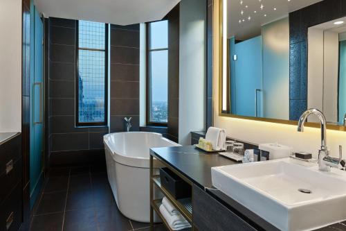 ein Badezimmer mit einer Badewanne, einem Waschbecken und einem Spiegel in der Unterkunft W Minneapolis - The Foshay in Minneapolis