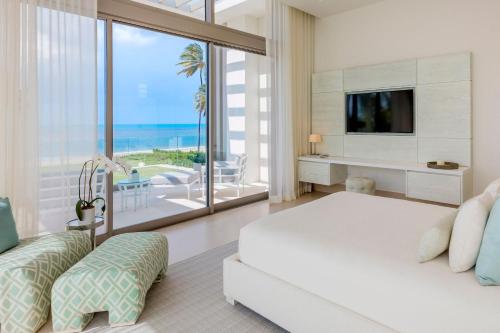 a bedroom with a bed and a tv and a balcony at St. Regis Bahia Beach Resort, Puerto Rico in Rio Grande