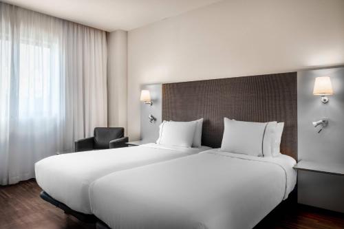 un grande letto bianco in una camera d'albergo di AC Hotel Gijón by Marriott a Gijón