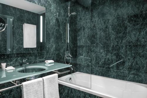a bathroom with a tub and a sink and a shower at AC Hotel Gijón by Marriott in Gijón