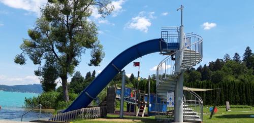 Un tobogán azul en un parque junto al agua en Ferienwohnung Schellander Privatstrand en Velden am Wörthersee