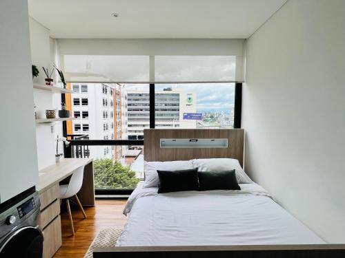 ein Schlafzimmer mit einem Bett und einem großen Fenster in der Unterkunft Apartaestudio en el Chico in Bogotá