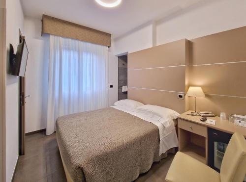 a hotel room with a bed and a desk and a window at Hotel Tiffany in Marina di Massa