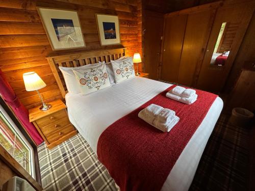 a bedroom with a large bed with towels on it at Pucks Glen Lodges in Dunoon