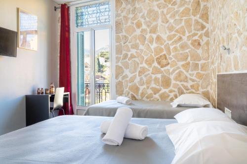 2 letti in una camera con parete in pietra di Hotel De Belgique à Menton a Mentone