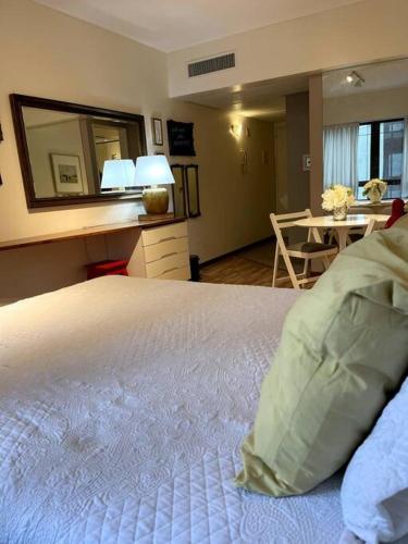 1 dormitorio con cama con espejo y mesa en escapada porteña en Buenos Aires