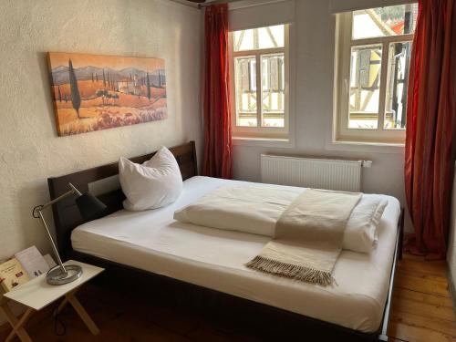 a bedroom with a white bed with two windows at Boarding House Obernburg in Obernburg am Main