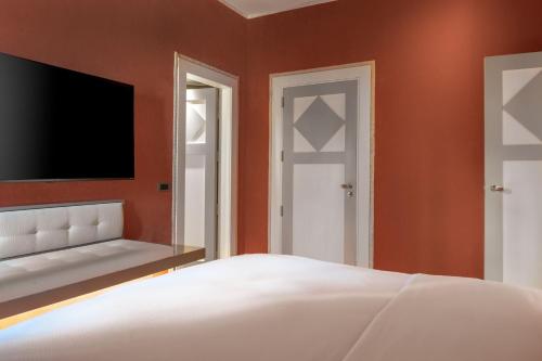 a bedroom with a bed and a flat screen tv at Santo Mauro, a Luxury Collection Hotel, Madrid in Madrid