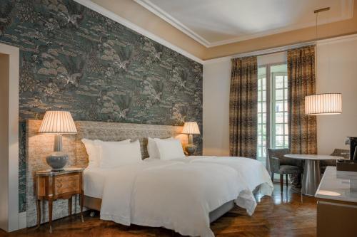 a bedroom with a large white bed and a wall mural at Santo Mauro, a Luxury Collection Hotel, Madrid in Madrid