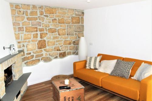 an orange couch in a living room with a stone wall at Appartement Gensungen in Felsberg