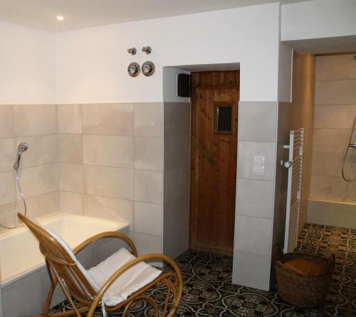 uma casa de banho com uma banheira e uma cadeira em frente a uma banheira em Appartement Gensungen em Felsberg
