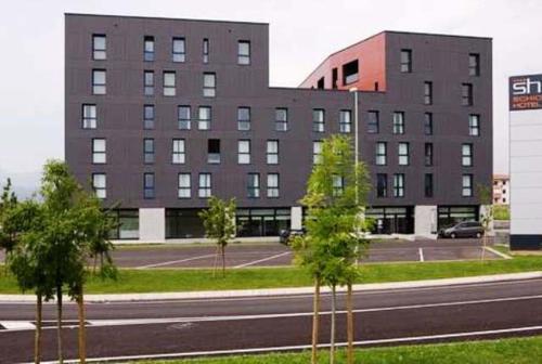 a building on the side of a street with trees at Schio Hotel in Schio