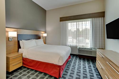 a hotel room with a bed and a flat screen tv at TownePlace Suites by Marriott Houston Northwest Beltway 8 in Houston