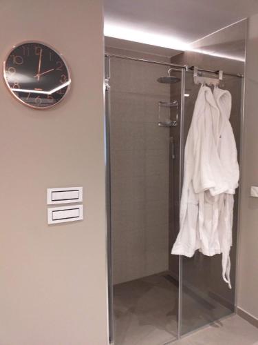 a bathroom with a shower and a clock on the wall at Spa Pleasure Apartman in Novi Sad