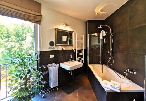 a bathroom with a tub and a sink and a mirror at Hotel Gutsmühle in Obernburg am Main