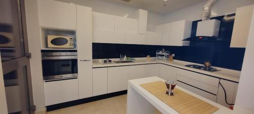 a kitchen with white cabinets and a blue wall at فيلا ضاحية الرمال in Riyadh