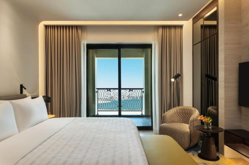 a bedroom with a bed and a chair and a window at Le Royal Méridien Place Vendôme Lusail in Doha