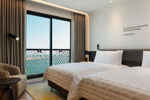 a hotel room with two beds and a large window at Le Royal Méridien Place Vendôme Lusail in Doha
