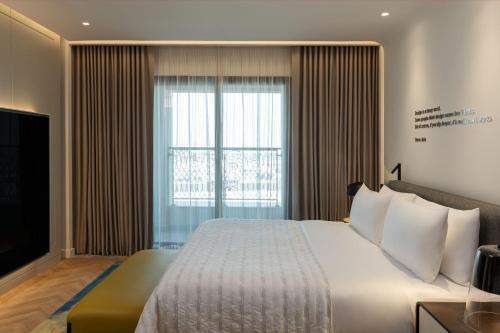a bedroom with a large bed and a large window at Le Royal Méridien Place Vendôme Lusail in Doha