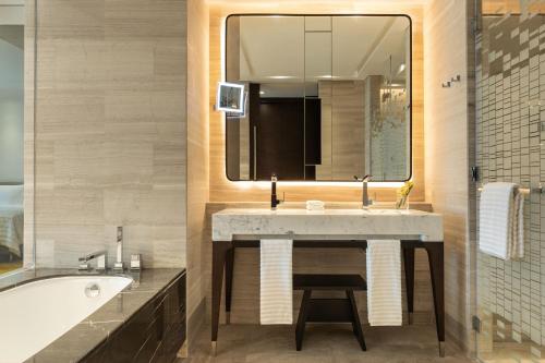 a bathroom with a sink and a tub and a mirror at Le Royal Méridien Place Vendôme Lusail in Doha
