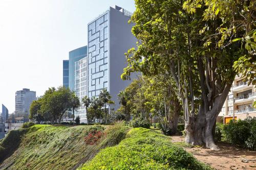 un parc arboré et un grand bâtiment dans l'établissement AC Hotel by Marriott Lima Miraflores, à Lima