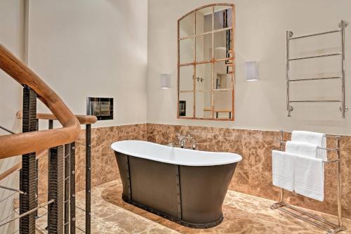a bathroom with a large tub and a mirror at Augustine, a Luxury Collection Hotel, Prague in Prague