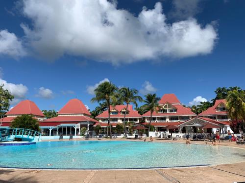 a pool at a resort with palm trees and buildings at T3 LES PIEDS DANS L'EAU à ST ANNE in Sainte-Anne