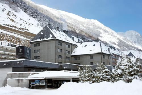 a building with snow on it in front of a mountain at Hotel AC Baqueira Ski Resort, Autograph Collection in Baqueira-Beret