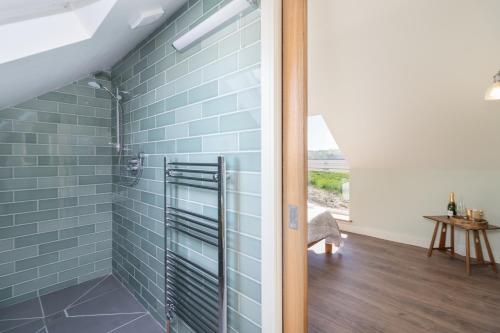 a bathroom with a shower with blue tiles at Green End Farm Cottages - The Cow Barn in Goathland