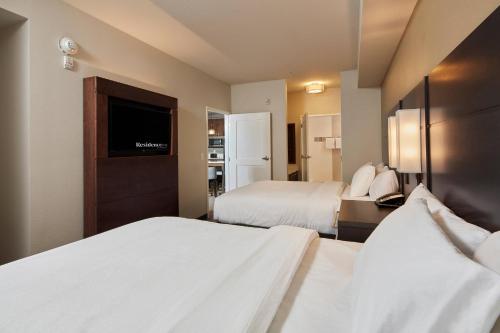 a hotel room with two beds and a flat screen tv at Residence Inn Sacramento Davis in Davis