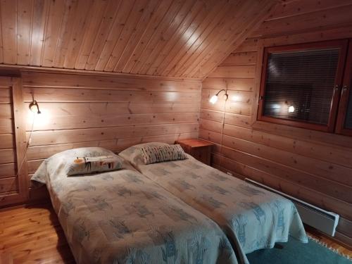 um quarto com 2 camas num chalé de madeira em Vihreä Helmi em Kuusamo