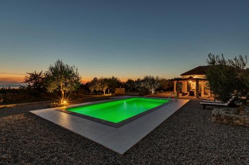 a green pool in a yard with a house at Villa Natura Makarska in Makarska